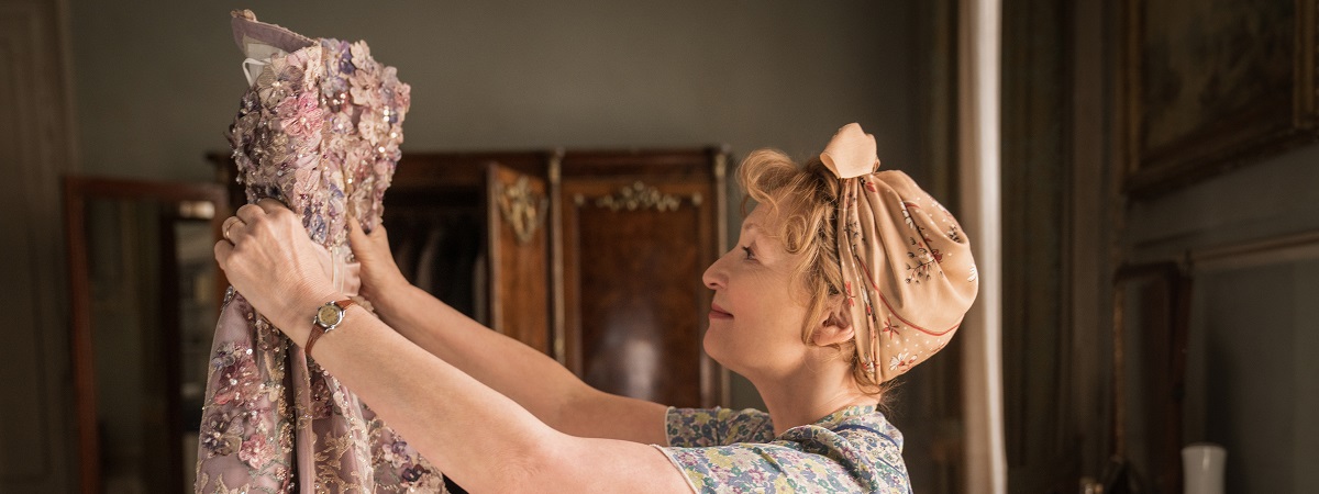 Lesley Manville holds a dress in Mrs Harris Goes To Paris