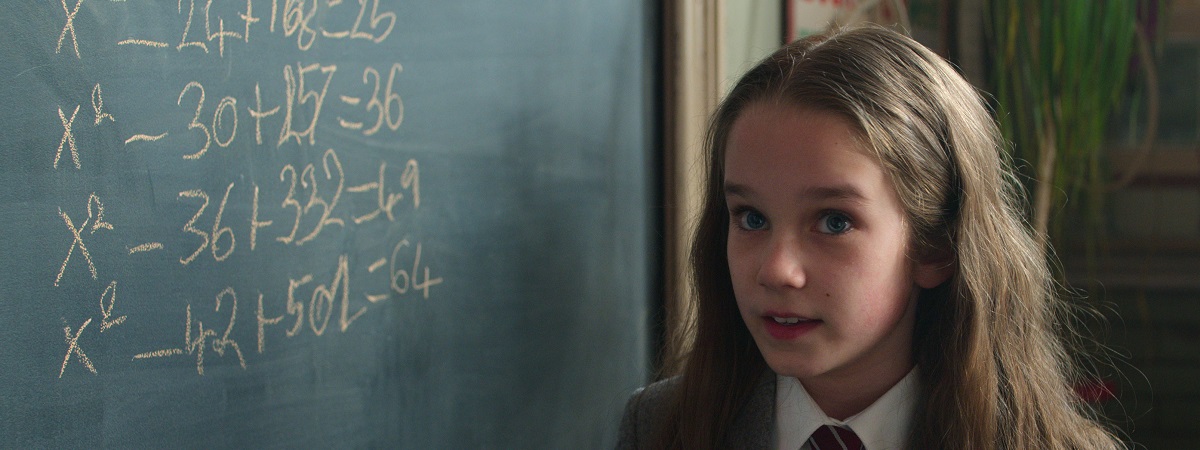 Matilda, played by Alisha Weir, stands next to a blackboard with a number of equations