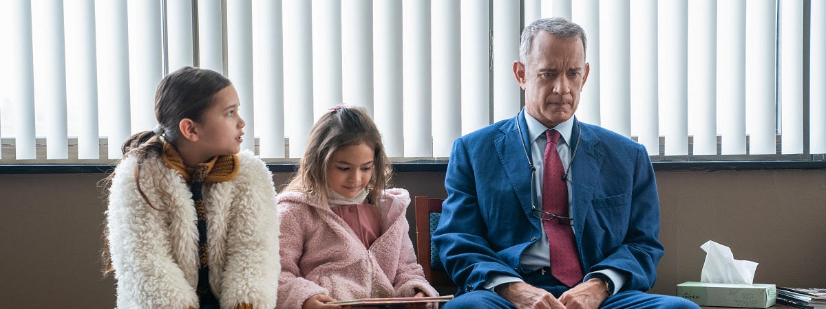 A man played by Tom Hanks sits in a waiting room with two children in A Man Called Otto