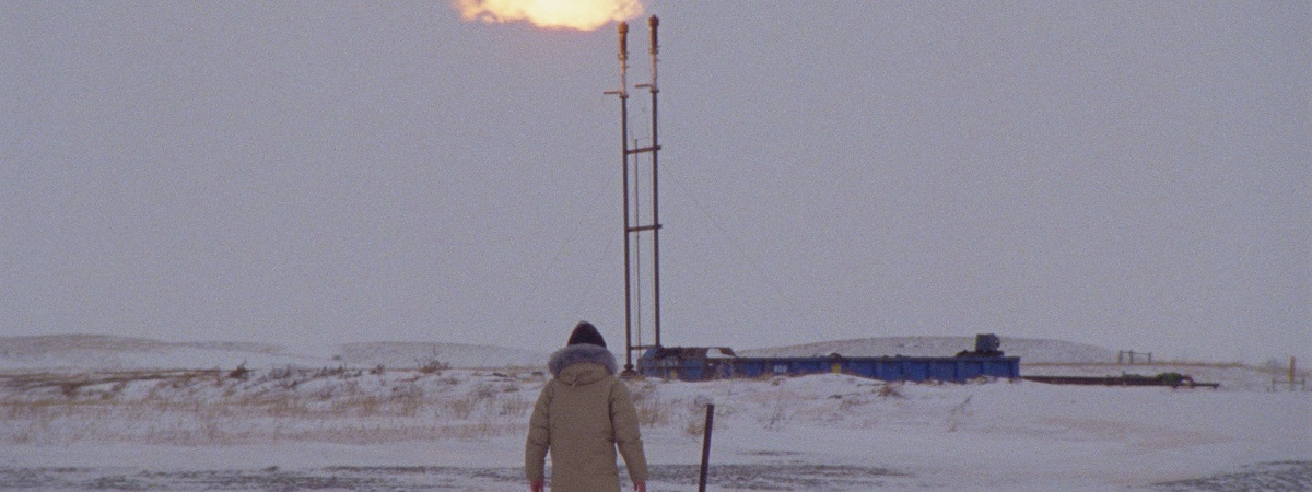 A person watches on as flames come out from the top of a pipeline in How to Blow Up a Pipeline