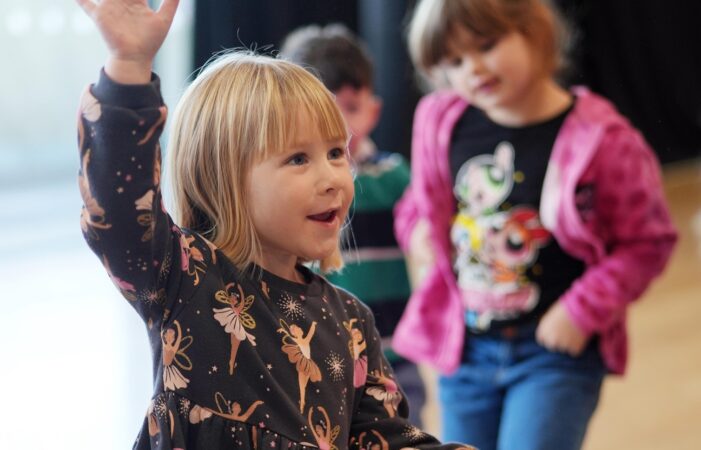 A young person dances as two young people look on in a promotional image for Bishop Auckland Town Hall Youth Theatre.