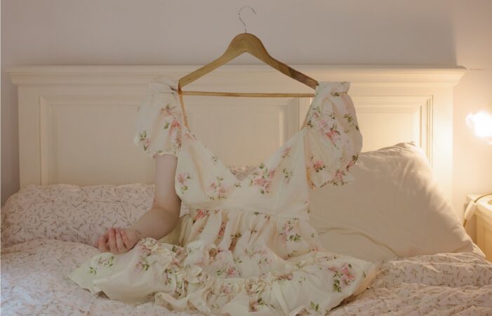 An image of a dress on a coat hanger with one arm above an illustration of a person with one arm and a half a birdcage on their head with butterflies flying out.