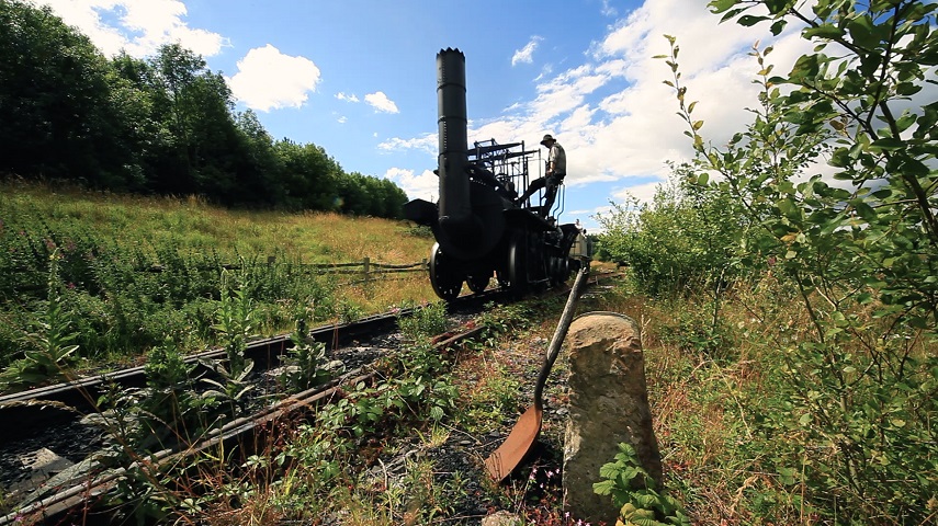 A steam engine on a railway track as part of a promotional image for Iron & Steam.