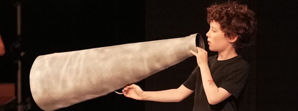 A young performer holds a megaphone in a photograph from Play In A Week.
